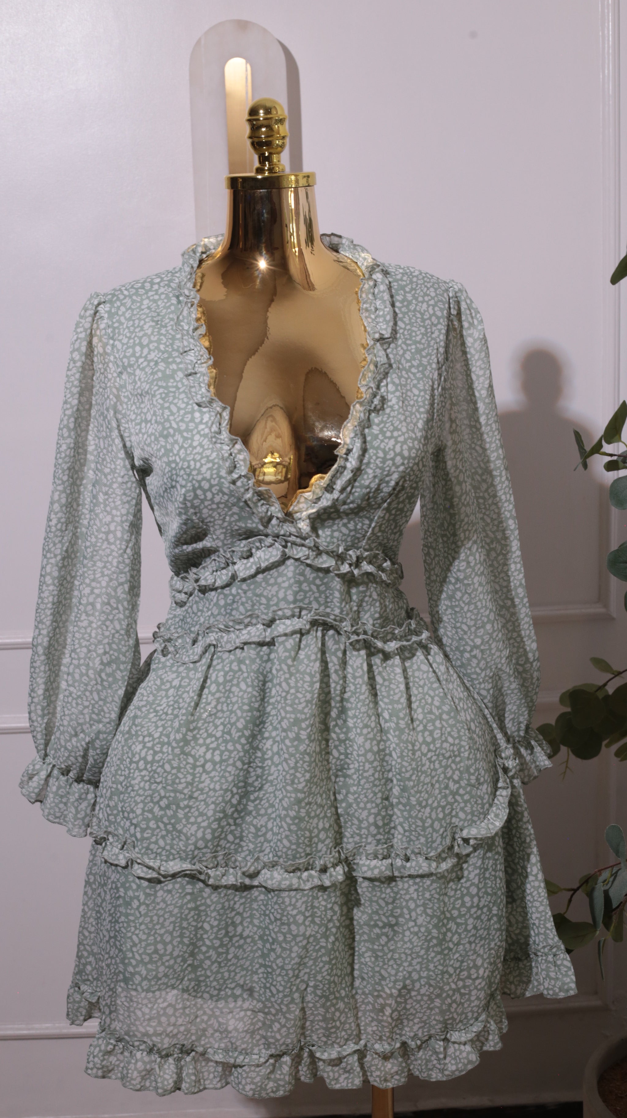 A Green Floral Mini Dress With A V-neck, Long Sleeves, A Shirred Waist, And Ruffled Tiers