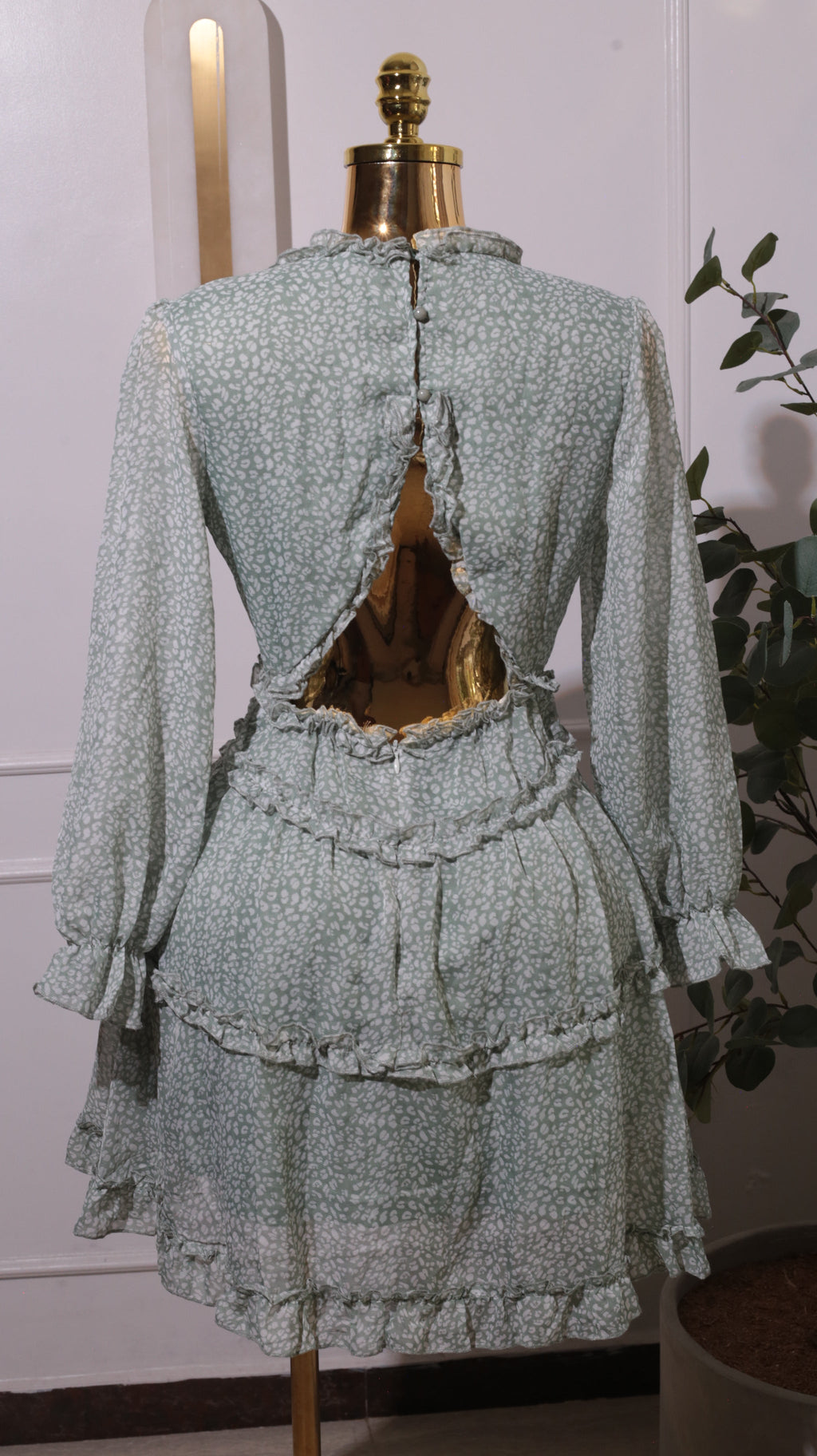 A Green Floral Mini Dress With A V-neck, Long Sleeves, A Shirred Waist, And Ruffled Tiers