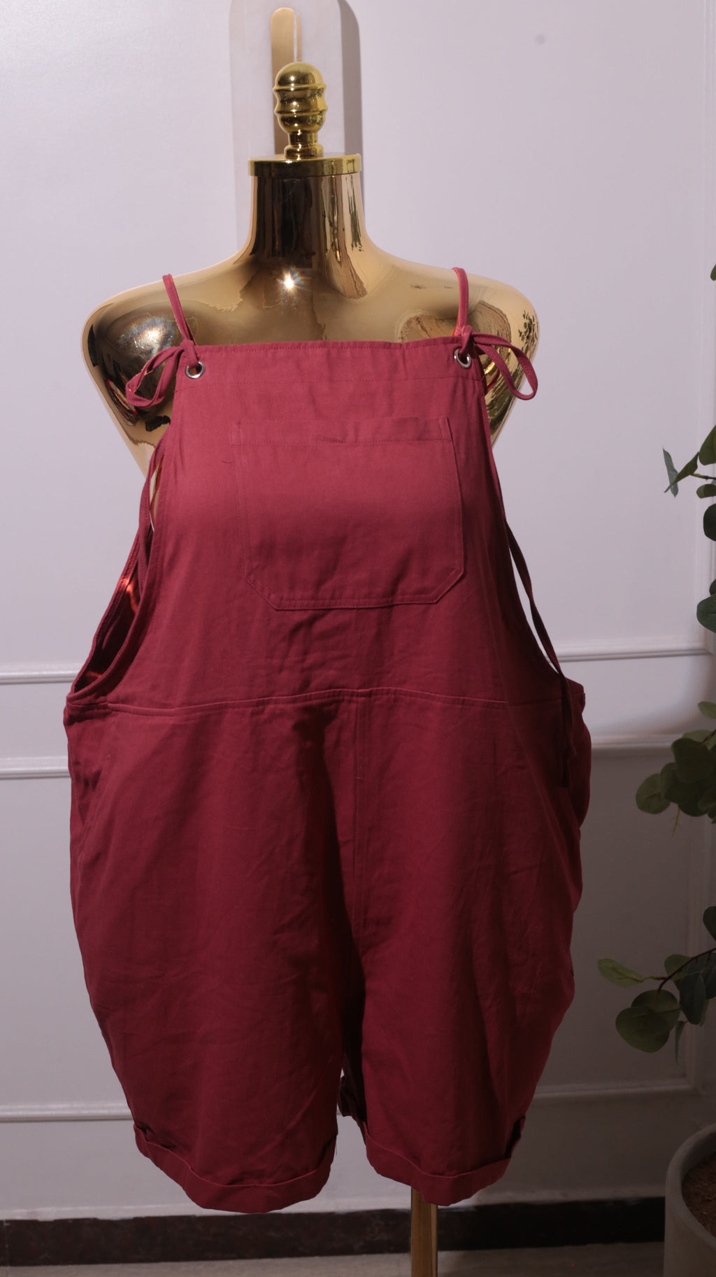 A Pair Of Women's Loose-fit Cotton Overalls Or Romper In A Reddish-brown Color, Featuring Adjustable Shoulder Straps, A